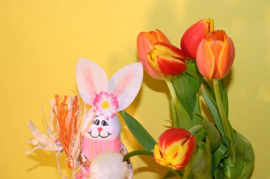 Dekoratif Paskalya tavşanı, arka planda lale demeti, yakın görüş, mutlu Paskalya konsepti. 