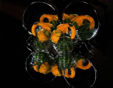 Aynanın yanındaki cam kasede olgun balkabağı yığını, yakın görüş. 