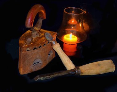 Eski metal demiri keskiyle ve mum lambasıyla koyu arkaplanda, yakın görüş 