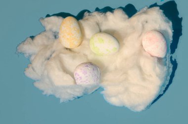 Dekoratif boyanmış Paskalya yumurtaları beyaz pamuklu, renkli arka plan, yakın görüş, kutlama konsepti 