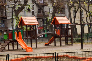 Sonbahar günü binaların yakınındaki bahçedeki parlak çocuk parkı 