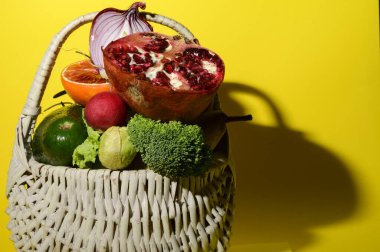 Olgun egzotik meyve ve sebze yığını demir sepetin içinde parlak arka planda, sağlıklı gıda kavramı 