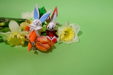 Parlak arka planda süslü Paskalya tavşanları olan güzel çiçekler, bahar konsepti, yakın görüş   