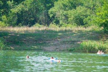 Güneşli bir günde nehirde yüzen insanların manzarası.