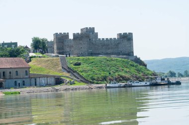 Güneşli bir günde tepede demirlemiş eski kalelerin olduğu gemilerin görüntüsü.