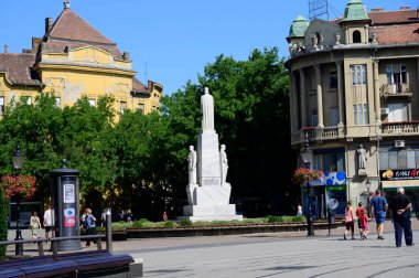 Güneşli bir günde şehrin caddesinde yürüyen insanlar.