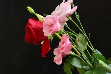 close up eustoma and rose flowers on black background 