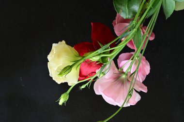 close up eustoma and rose flowers on black background 