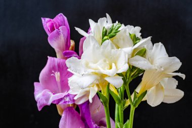 Siyah arkaplana karşı beyaz ve mor çiçeklerin düzenlenmesi