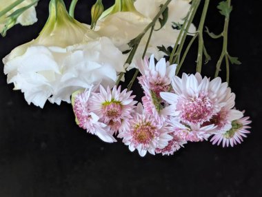 Koyu arkaplanda pembe ve beyaz çiçeklerin düzenlenmesi