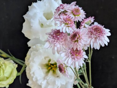 Koyu yüzeyde pembe ve beyaz çiçeklerin düzenlenmesi