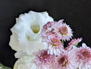 Koyu arkaplanda pembe ve beyaz çiçeklerin düzenlenmesi