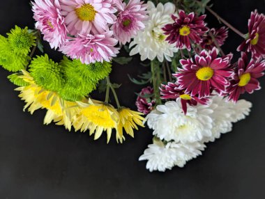 Koyu yüzeyde güzel dizilmiş renkli çiçekler.