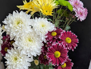 Beyaz sarı pembe çiçekleri de içeren renkli bir buket.