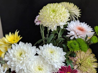 Arrangement of colorful flowers including white pink yellow green
