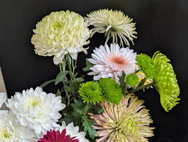 Koyu arkaplana karşı renkli çiçeklerin düzenlenmesi