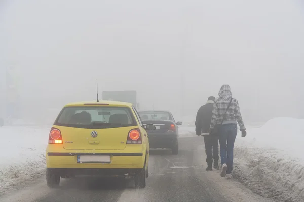 BUCHAREST - 15 FÉVRIER : Brouillard épais à Bucarest après une chute de neige massive le 15 février 2012. Les gens sont forcés de marcher à l'extérieur des trottoirs près des voitures de passage — Photo