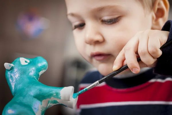 Boy painting ceramic figure — Stock Photo, Image