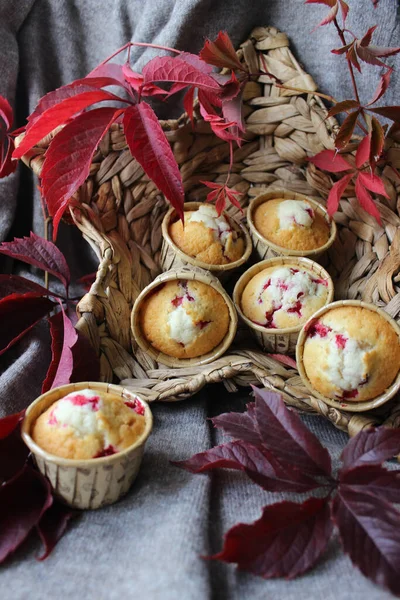 Os cupcakes frescos com recheio de cereja são colocados em uma cesta de vime e decorados com folhas de outono. — Fotografia de Stock