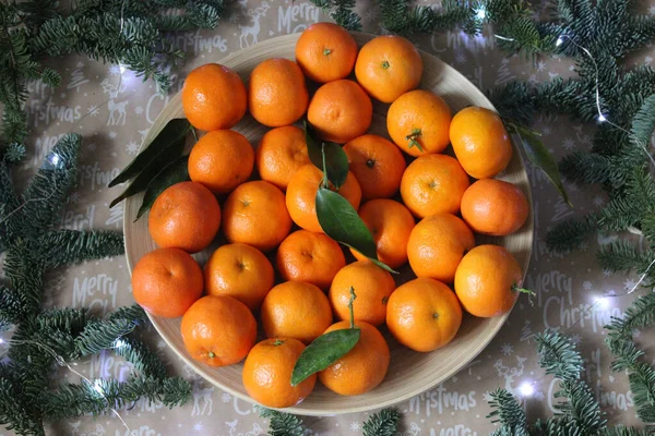 Mandarinen auf einem mit Weihnachtsgirlanden und Fichtenzweigen dekorierten Teller — Stockfoto