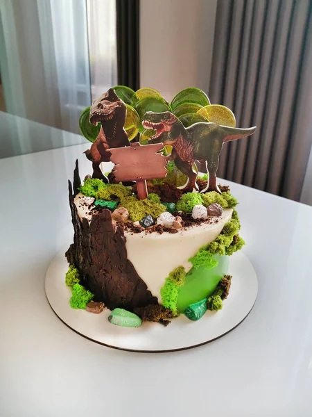 Sweet birthday cake with two stylized dinosaurs on the surface