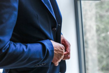 Bir adam mavi ceketini ilikliyor.