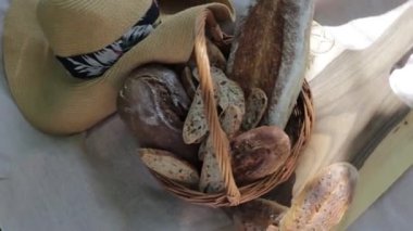 Kamera hasır bir sepetin üzerinde el işi ekmek ve hasır şapkayla hareket ediyor.