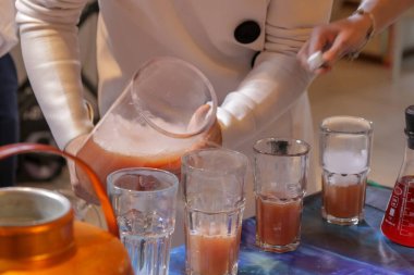 Garson içkiyi bardaklara doldurur.