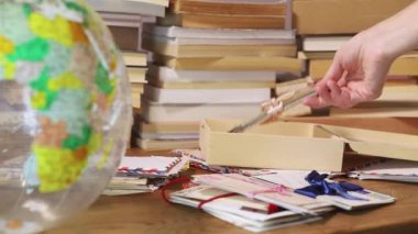 Eski kartpostalları tahta kutuya yerleştirmek, dünyanın ön planında, arka planda bir yığın kitap.