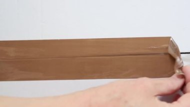 Yapışkan bandı beyaz karton kutudan çıkar.