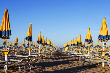 Güneşli bir günde kumsalda, mavi-sarı plaj şemsiyesiyle 