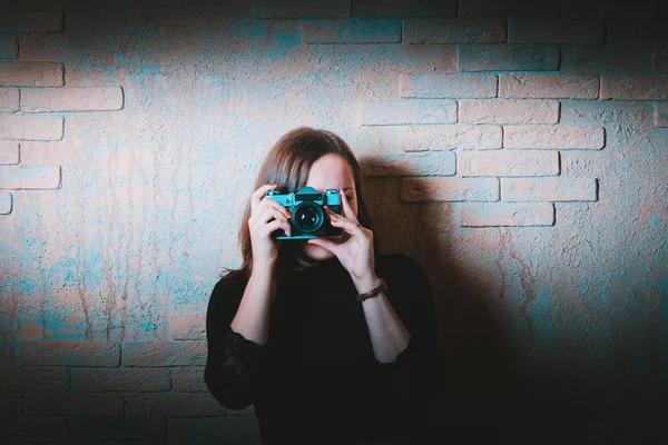 Meisje met een vintage camera in de buurt van bakstenen muur — Stockfoto