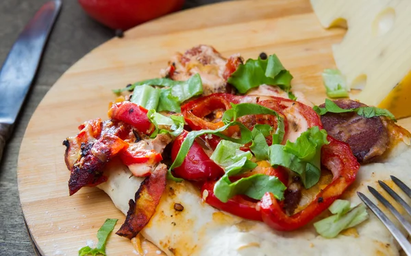 Irisan pizza dengan paprika, daging dan rempah-rempah di papan kayu — Stok Foto
