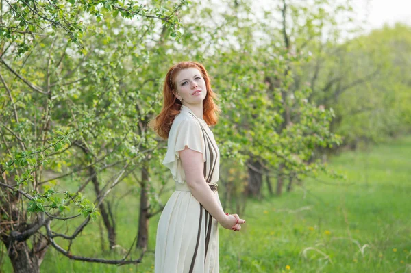 Bella ragazza dai capelli rossi passeggiate nel frutteto di mele — Foto Stock