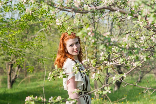 Krásná rusovlasá dívka chodí v jabloňový sad Royalty Free Stock Fotografie