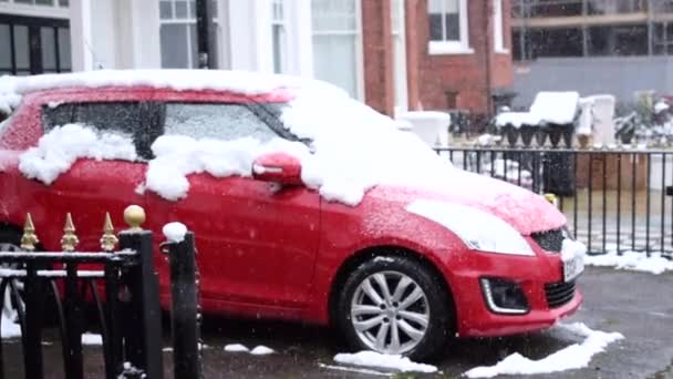 Carro vermelho estacionado por uma casa sob neve pesada. — Vídeo de Stock