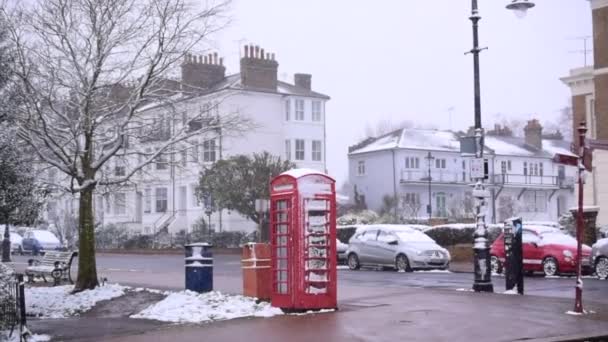 Vista de la calle en la ciudad inglesa con la casa y la gente bajo nieve pesada. — Vídeos de Stock