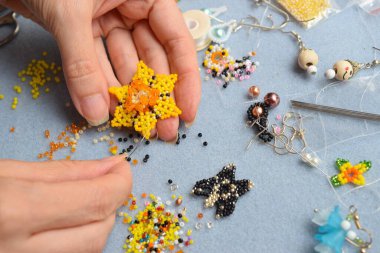 Tasarımcı küçük boncuklardan boncuklu bir çiçek yapıyor..