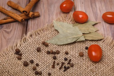 Kiraz domatesleri, corianderlar, ahşap bir yüzey üzerinde defne yaprakları.