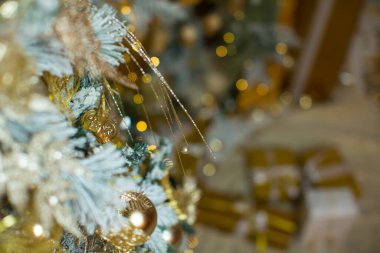 Tebrik kartı için altın Noel arkaplanı. Altın kaplamalı Noel ağacı, altın toplarla süslenmiş, oyuncaklar, çelenklerle süslenmiş yıldızlar. Mutlu Noeller, mutlu yıllar.!