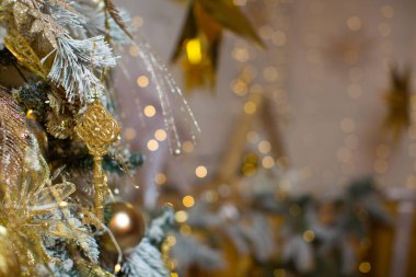 Tebrik kartı için altın Noel arkaplanı. Altın kaplamalı Noel ağacı, altın toplarla süslenmiş, oyuncaklar, çelenklerle süslenmiş yıldızlar. Mutlu Noeller, mutlu yıllar.!