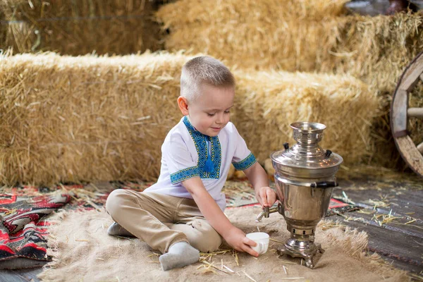Дитячий Хлопчик Вишитій Сорочці Сидить Мішку Самоваром Чай Тлі Тюків — стокове фото