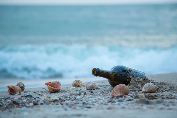 Uma Garrafa Deitada Praia Contra Fundo Conchas Rapana Ondas — Fotografia de Stock