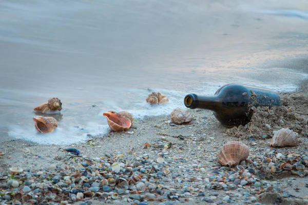 Flaska Som Ligger Stranden Mot Bakgrund Rapanskal Och Vågor — Stockfoto