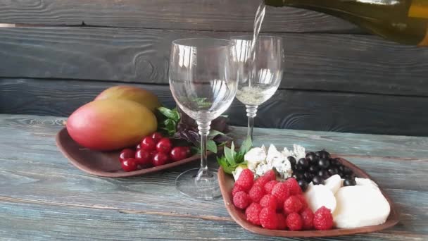 两个陶瓷碗 一个装有芒果 罗勒和薄荷糖 另一个装有黑醋栗 蓝奶酪 莫扎拉和覆盆子 两杯干白葡萄酒 木材背景 — 图库视频影像