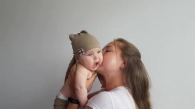 Anne, bej cüce takım elbiseli beş aylık oğlunun yanaklarından öpüyor. Ne olduğunu anlamıyor.