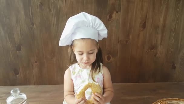 Трирічна Дівчинка Білій Сукні Шапка Випічки Їсть Великий Багель Фоні — стокове відео