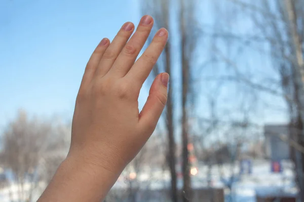 The girl\'s hand rests on the glass of the window. Loneliness concept