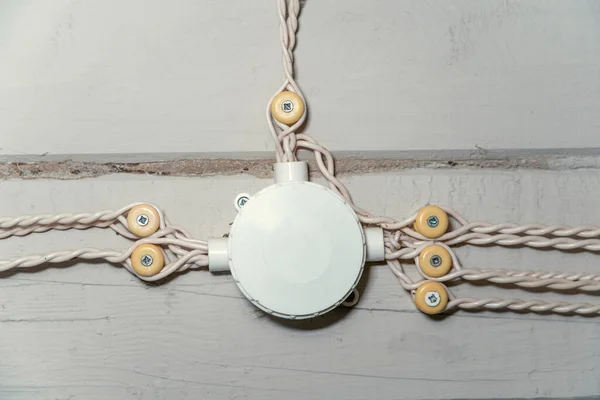 retro wiring in a wooden house. white twisted cables are connected in an electrical box on a wooden beam wall