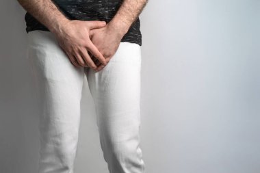 Beyaz kotlu bir adam, cinsel organına el ele tutuşuyor. Erkekler için hastalık. Cinsel yolla bulaşan enfeksiyonlara karşı korunma kavramı. Testis kanseri.